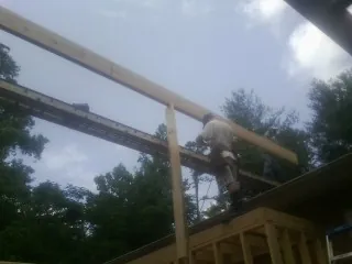 Carpenter setting a ridge beam over a new addition frame — Ice Dam Removal by Roofing Brothers in Phippsburg