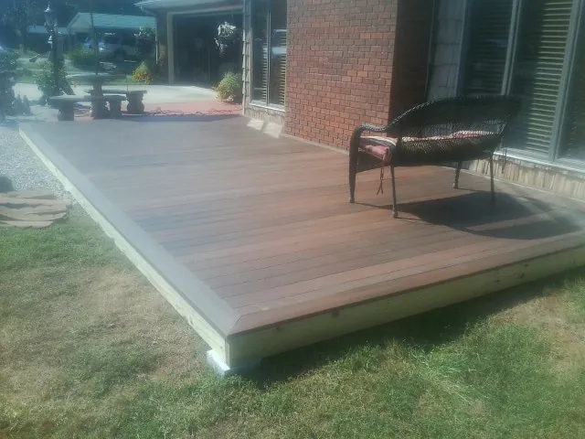 New wood deck and wicker chair beside a brick house in Phippsburg