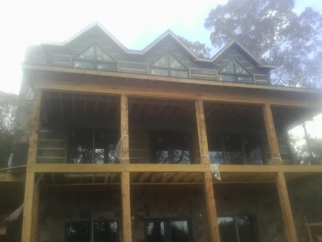 Dormers and porch framing on a large log home under construction — Roof Coating work by our crew in Phippsburg