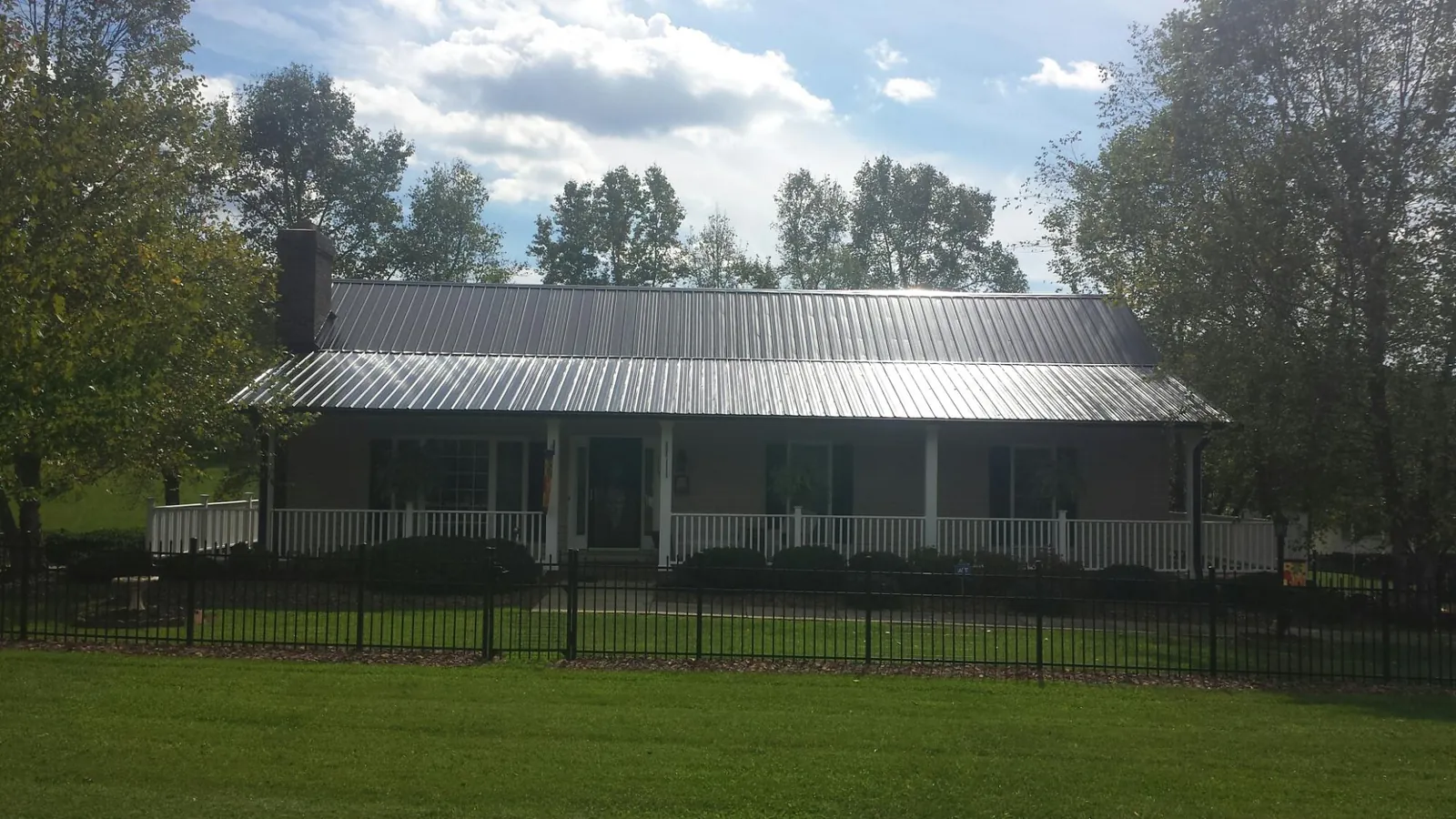 Gray metal roof on a brick ranch with a full width front porch — Gutter Guard Installation work by our crew in Phippsburg