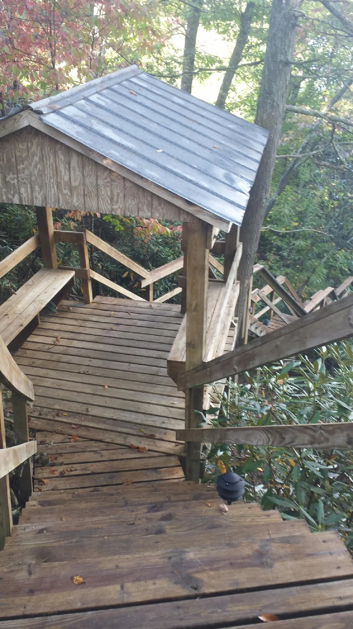 Metal roofed shelter over wooden steps on a wooded walkway — Skylight Repair & Installation work by our crew in Phippsburg