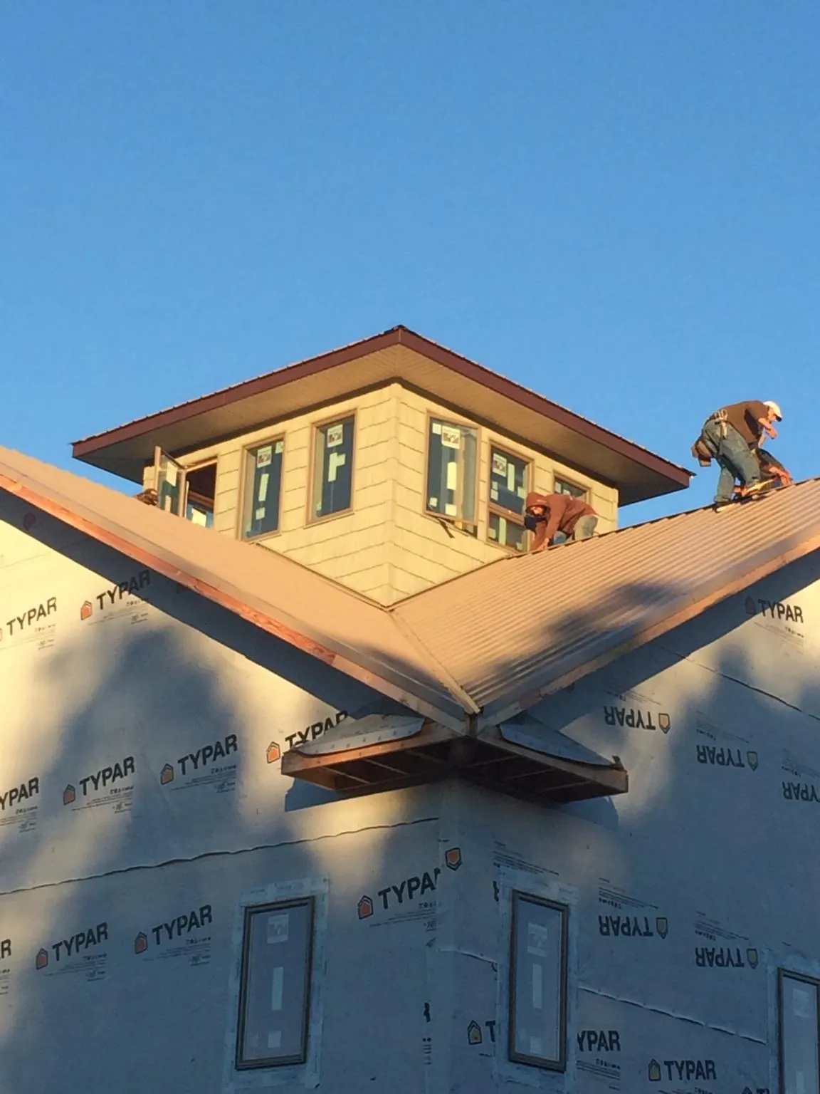 Roofers working around a rooftop cupola on a new metal roof at sunset — Roof Waterproofing in Phippsburg by Roofing Brothers